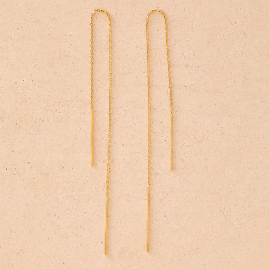 Gold chain earrings on a beige background