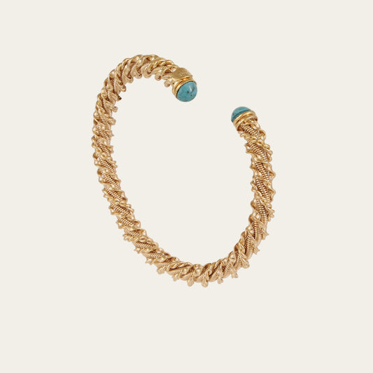 Gold bracelet with turquoise beads on a light beige background
