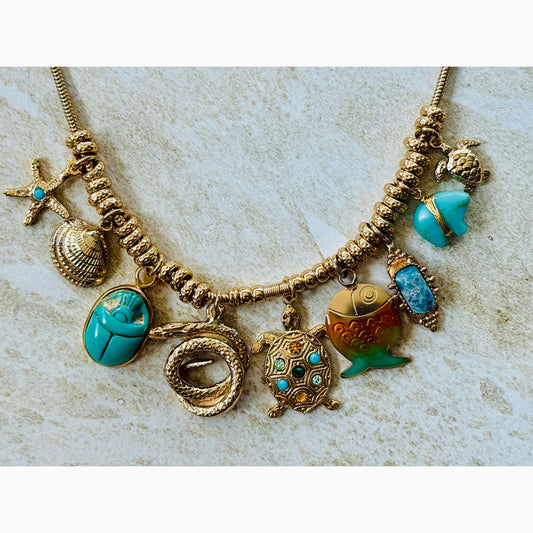 Necklace with various charms including a turtle, fish, and shell on a textured surface