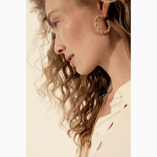 Gold braided hoop earrings worn by model in side profile view.”