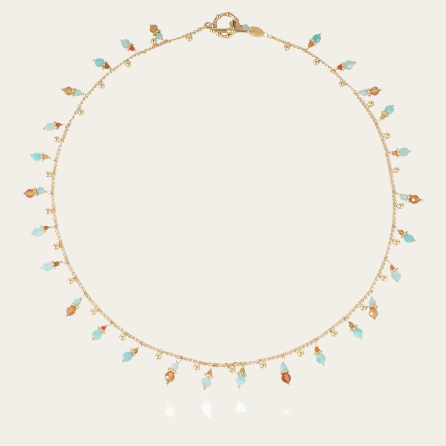 A gold-plated necklace with a series of tangerine-colored gemstone pendants and small pearls.