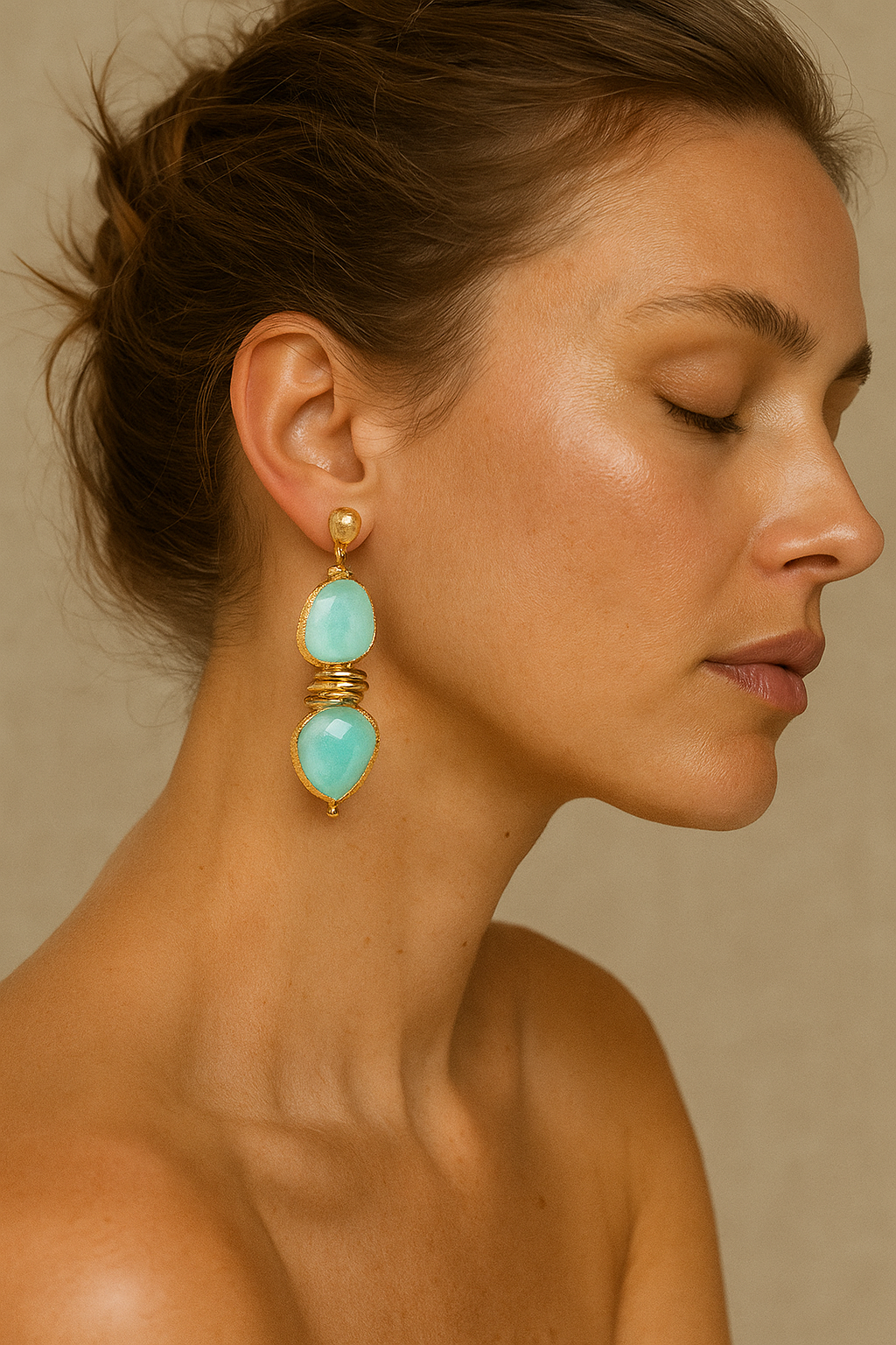 Woman wearing turquoise earrings with gold accents against a neutral background