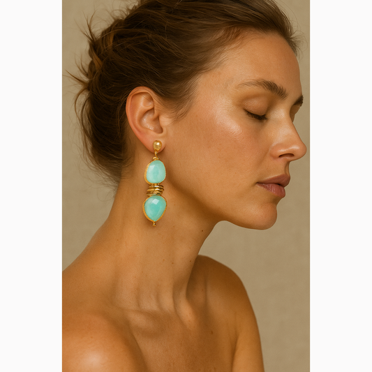 Woman wearing turquoise earrings with gold accents against a neutral background