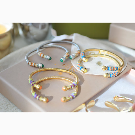 Colorful beaded bracelets on a pink surface with a green background