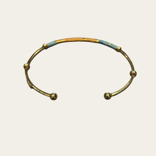 gold plated bangle with coloured threads on neutral backdrop