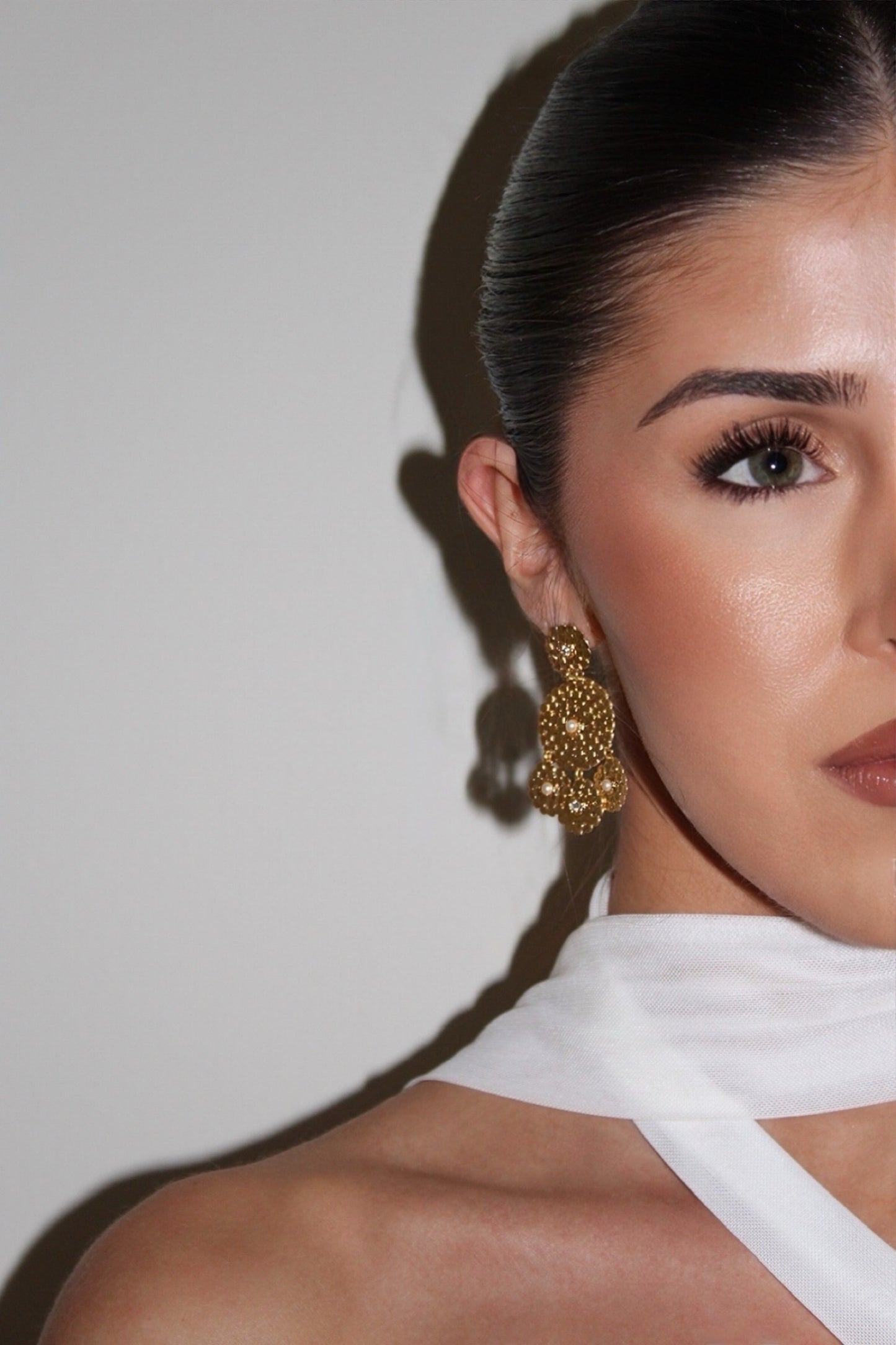 Woman wearing gold earrings with a neutral background