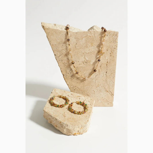 coloured stone hoops on marble stone and necklace in background