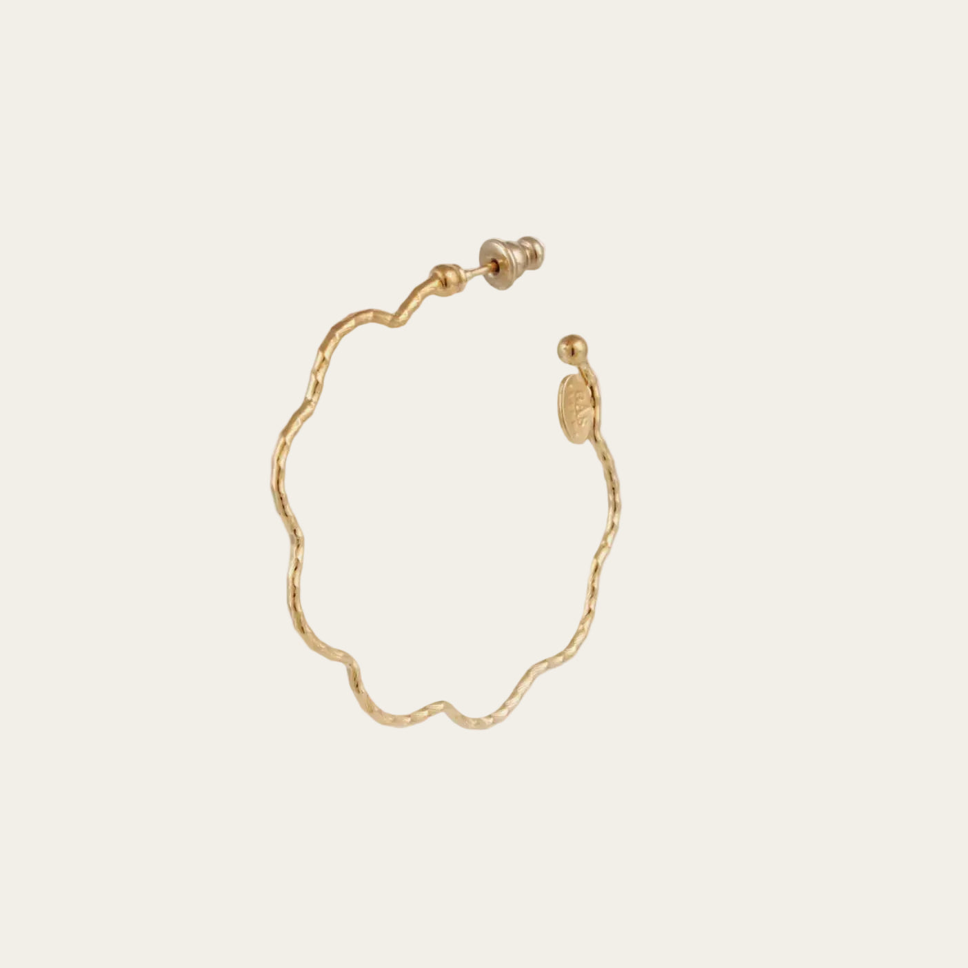 Gold earrings on a beige background