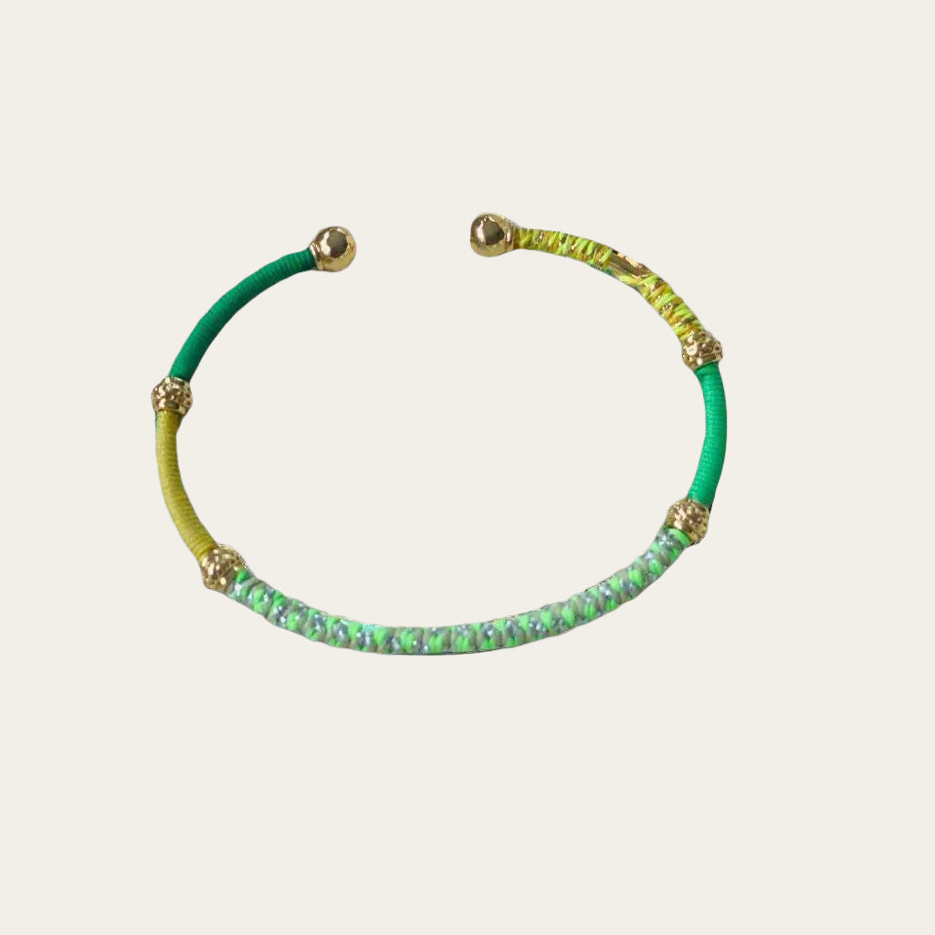 Green & Yellow threaded bracelet on light grey surface