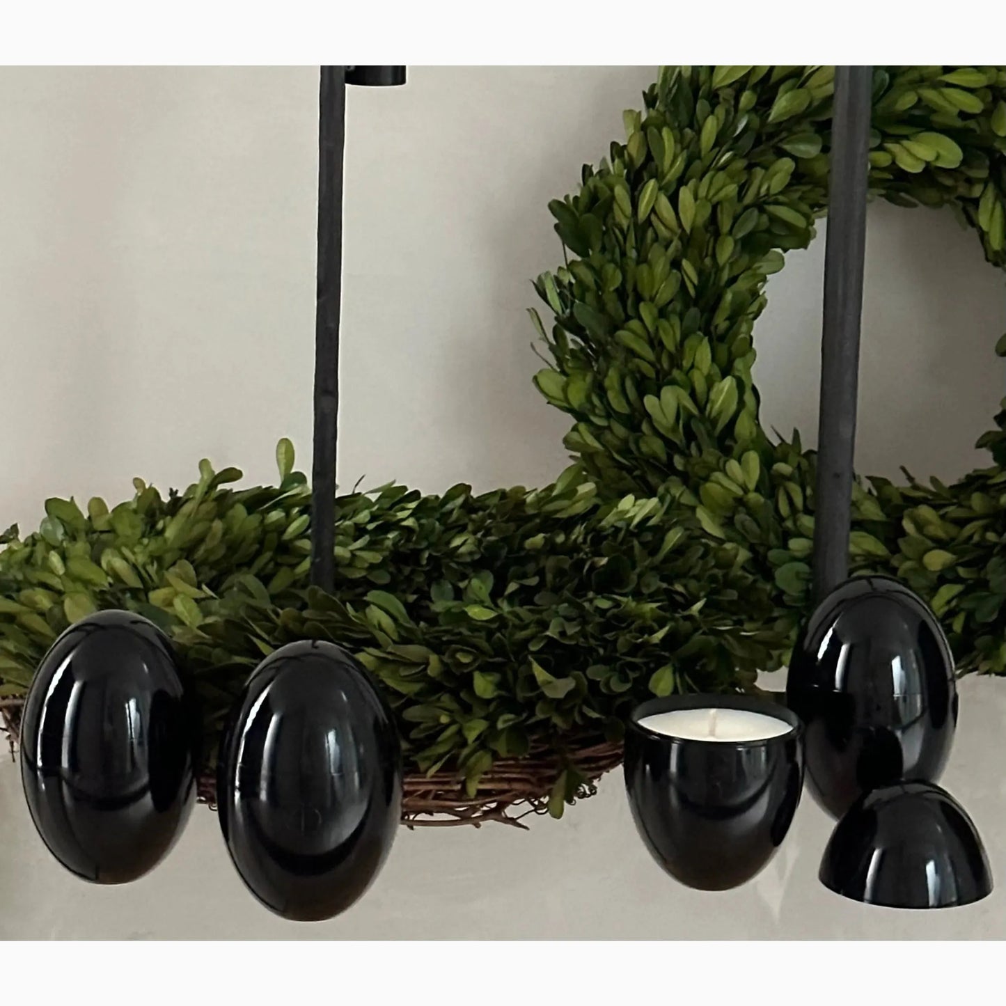 Black Omorfi candles in situ with decorative green wreaths in background
