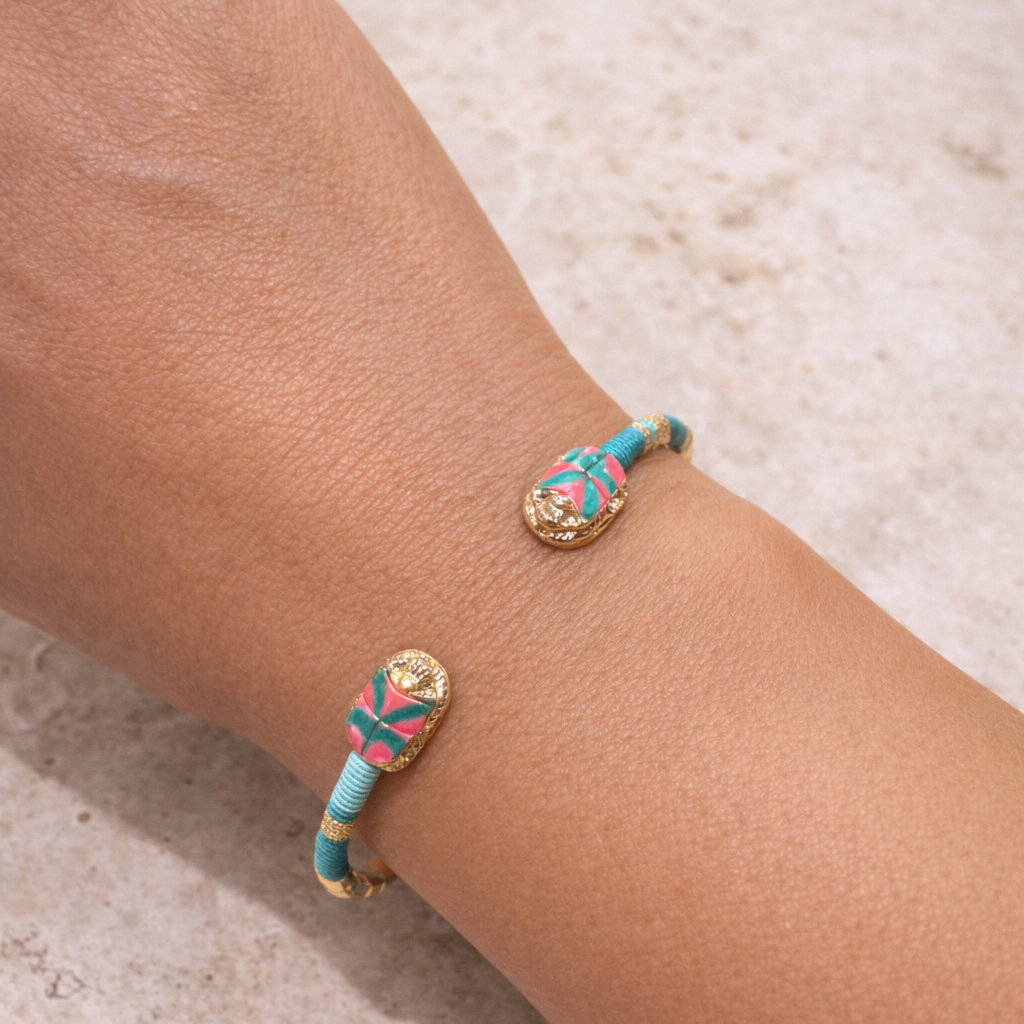 Bracelet with turquoise and gold design on a wrist against a neutral background