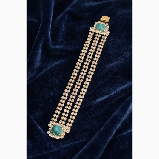 Bracelet with turquoise stones and gold accents on a dark blue velvet background