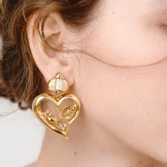 Gold heart-shaped earring worn by a person