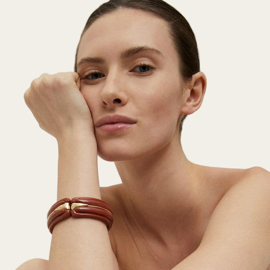 Woman wearing a brown leather bracelet on a plain background