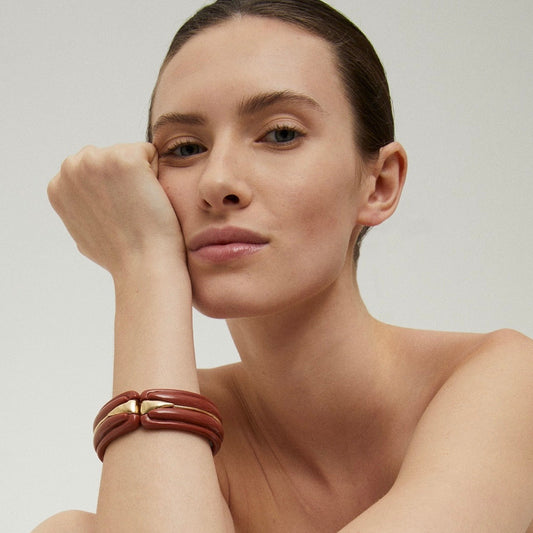 Woman wearing a brown leather bracelet on a plain background