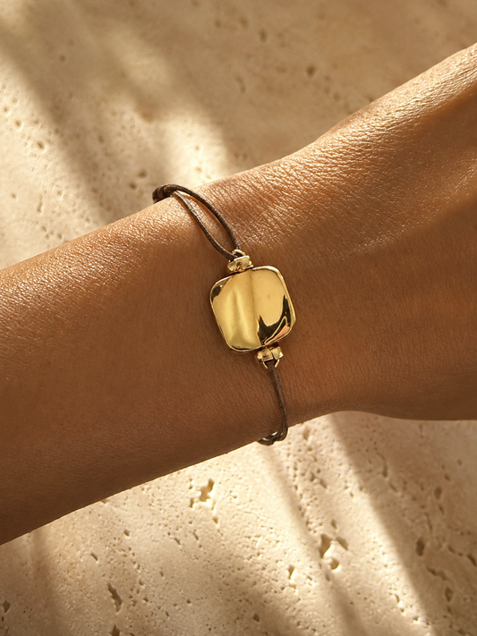Gold bracelet on a wrist with a neutral background