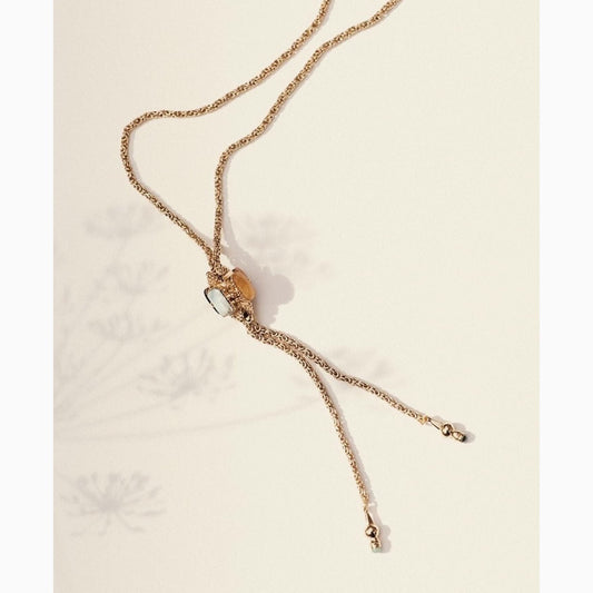 long gold necklace with stone talisman on neutral background