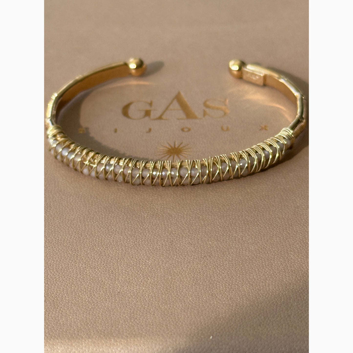 Gold bracelet with a Gas Bijoux box on a beige background
