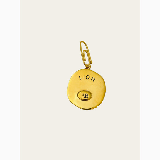 Gold pendant with 'LION' engraved on a light gray background.
