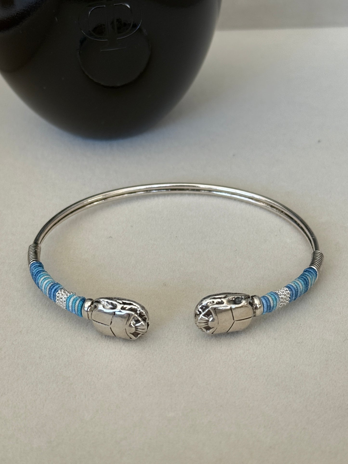 Silver bracelet with blue accents on a light gray background