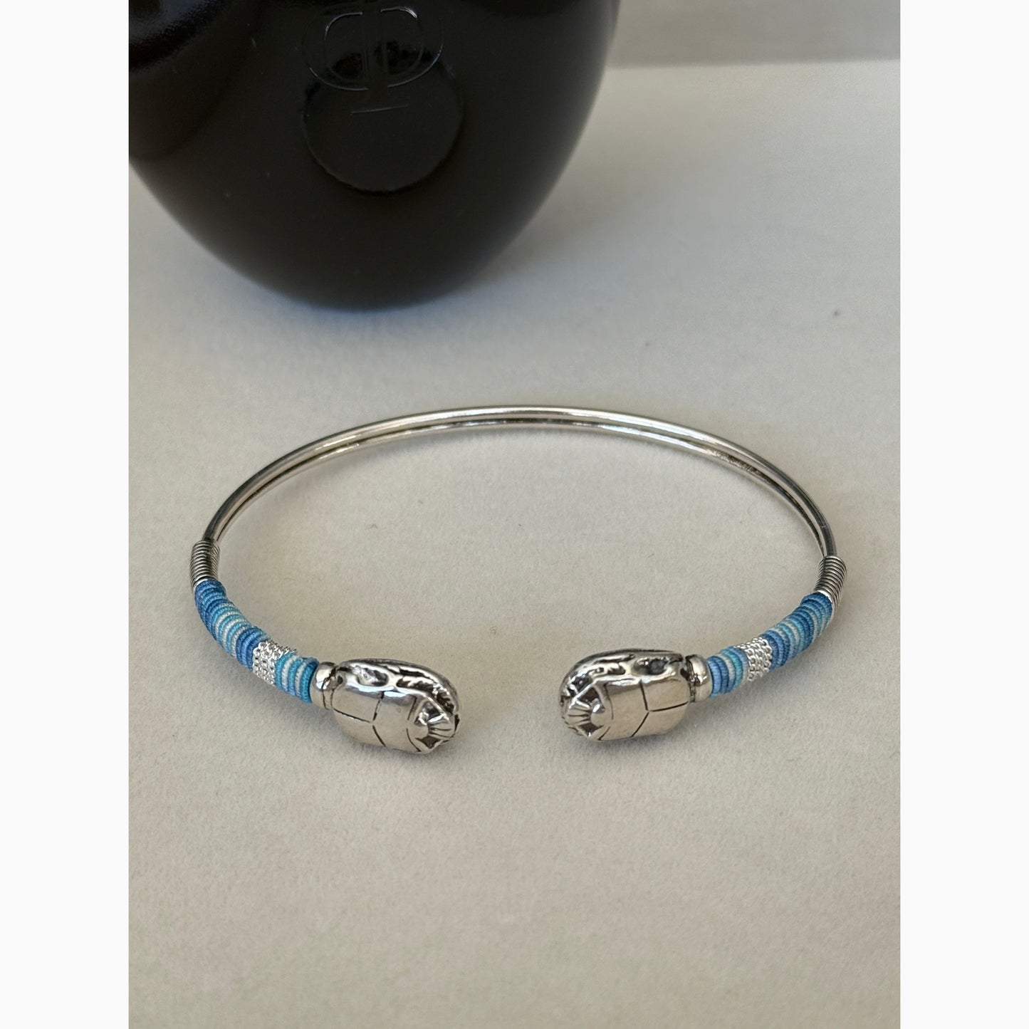 Silver bracelet with blue accents on a light gray background
