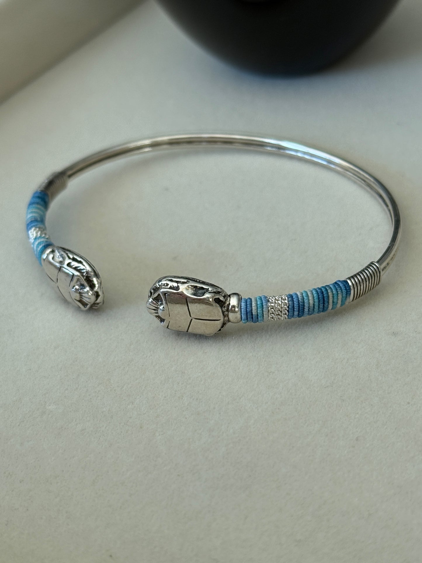 Silver bracelet with blue accents on a light gray background