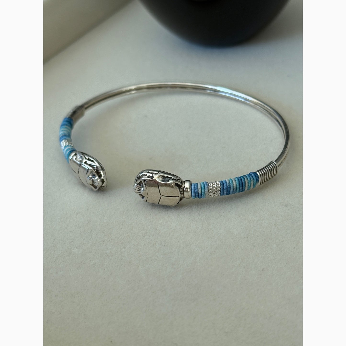Silver bracelet with blue accents on a light gray background
