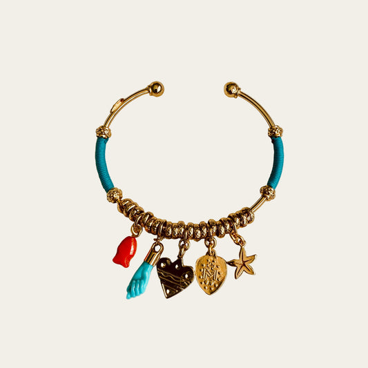 Bracelet with turquoise bead and gold charms on a light gray background