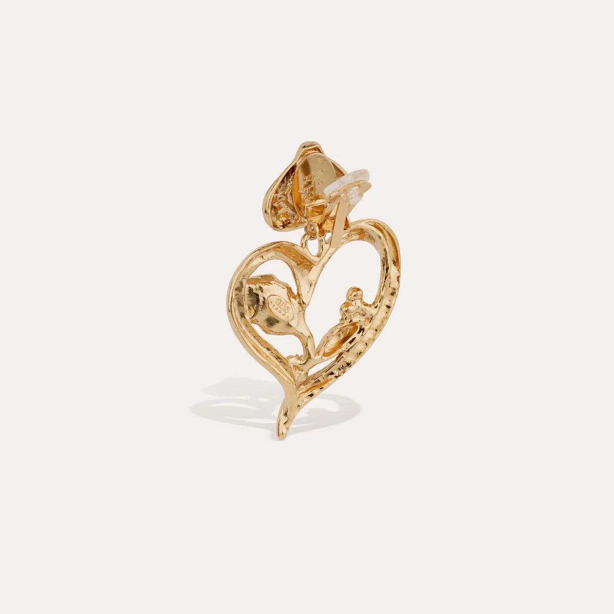 Gold heart-shaped pendant with floral design on a light beige background