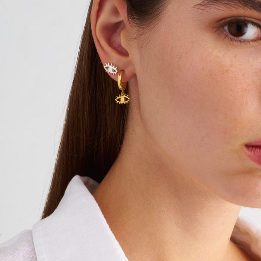 Close-up of a person wearing gold earrings with a white shirt background