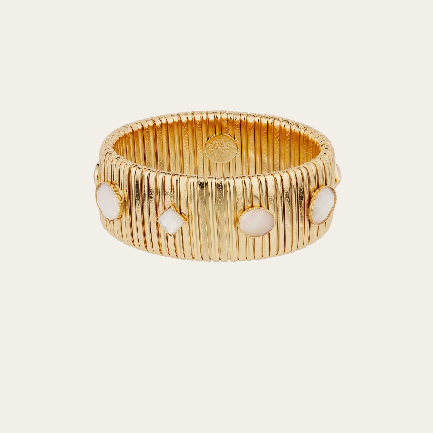 Gold bracelet with white stones on a light beige background