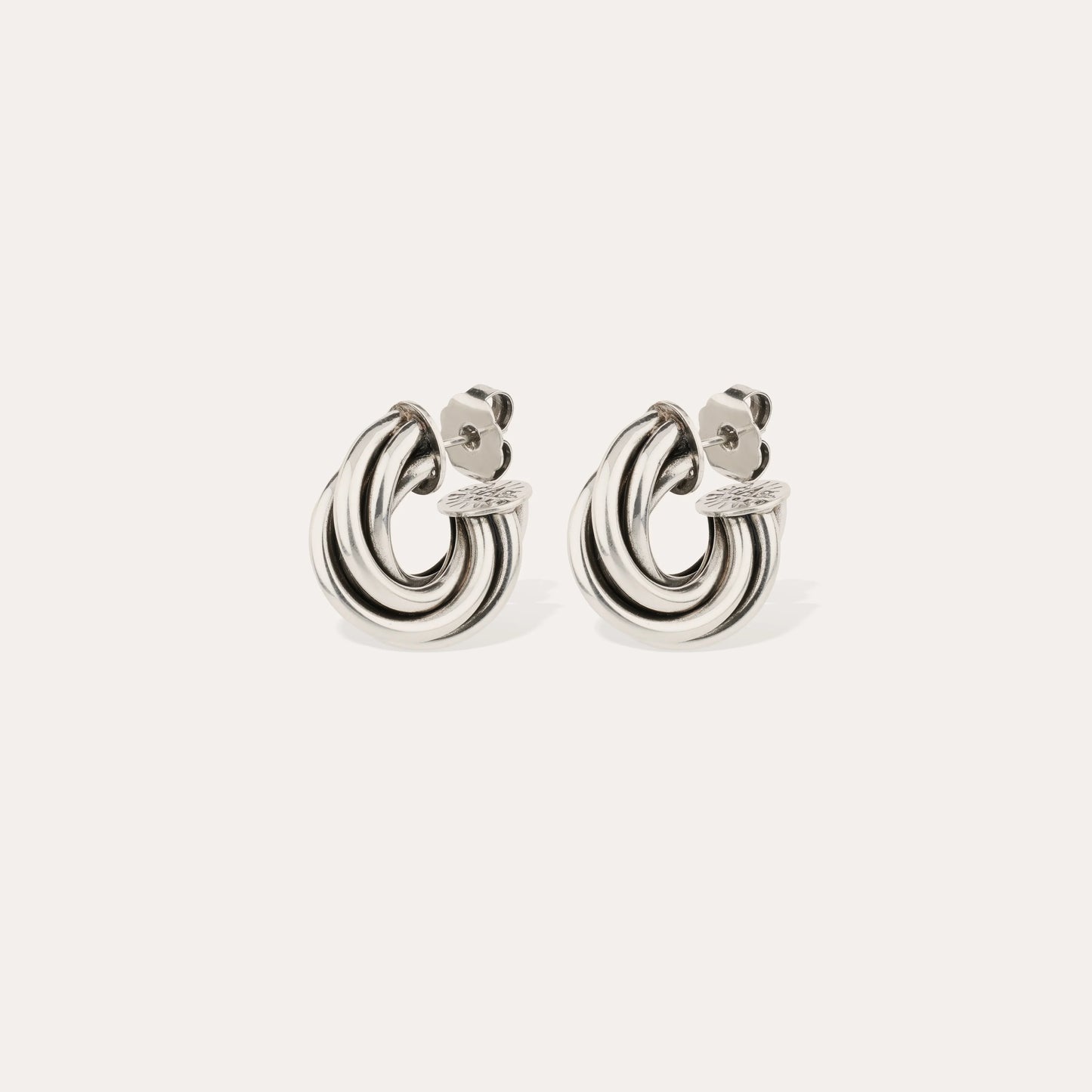 Pair of silver hoop earrings on a light beige background