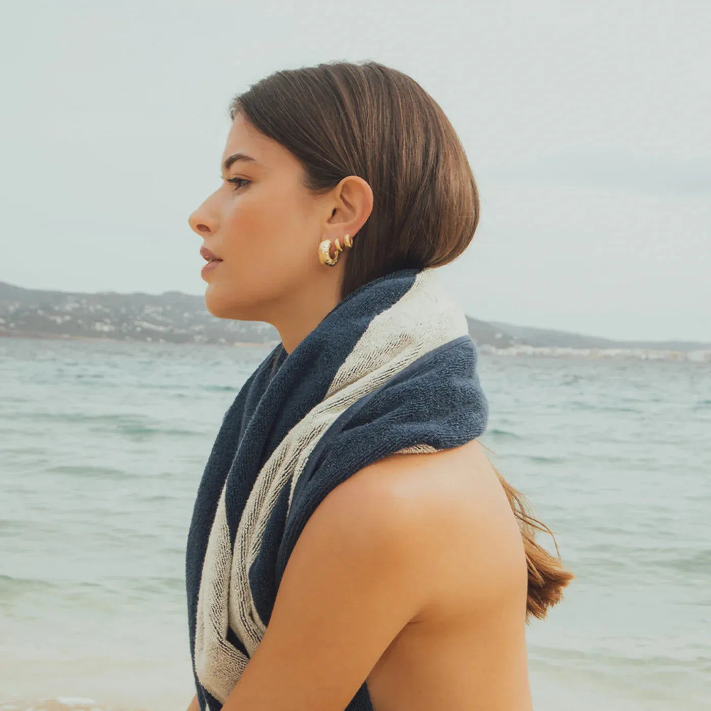 Agapee Anilla mini gold earrings on model at beach