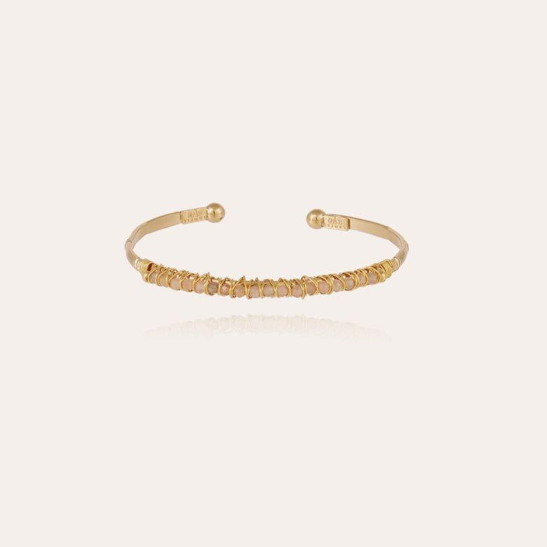 A gold-plated bracelet with pink quartz gemstones and metallic threads on a white background.