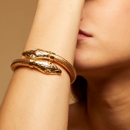 Gold snake bracelet on a wrist with a blurred background