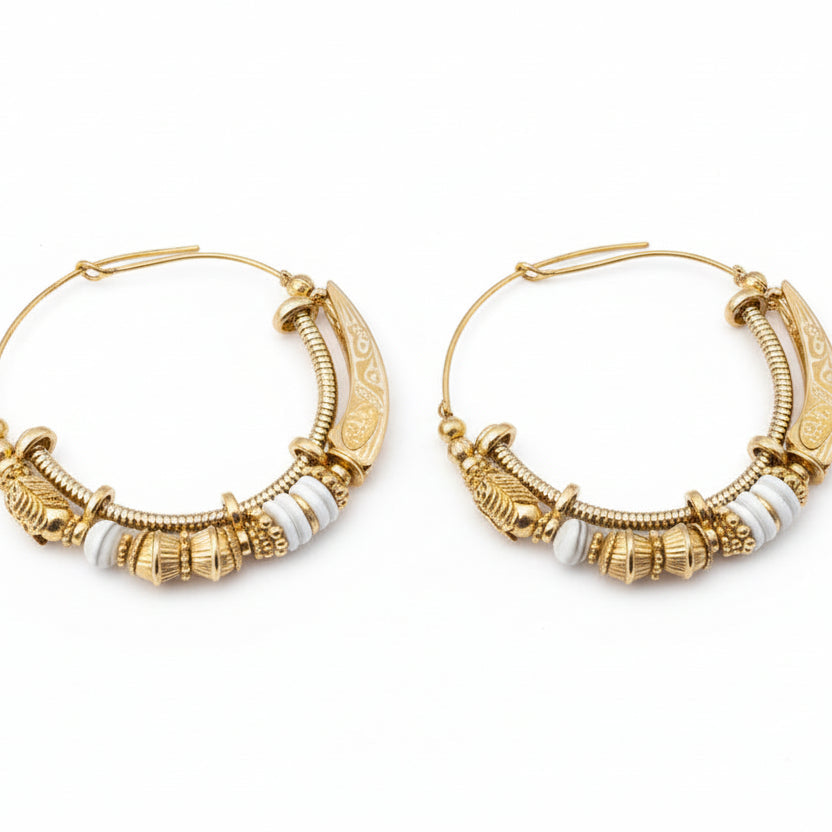 Pair of ornate gold hoop earrings on a gray background