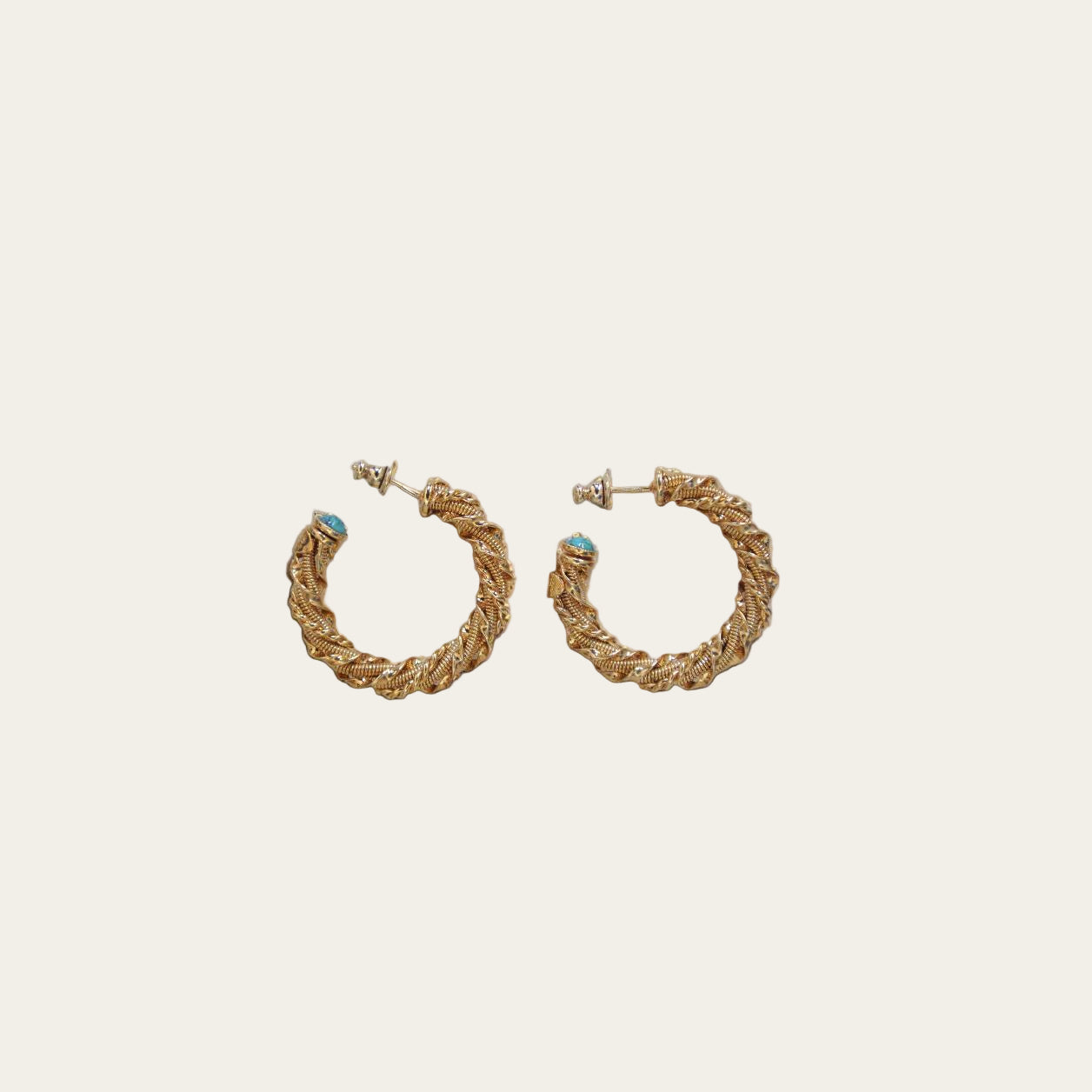 Gold braided hoop earrings with turquoise stones on a neutral background