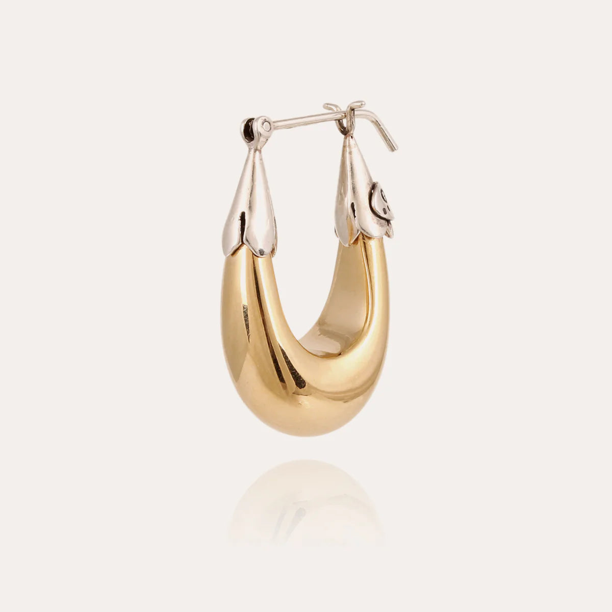 Gold hoop earring on a light beige background