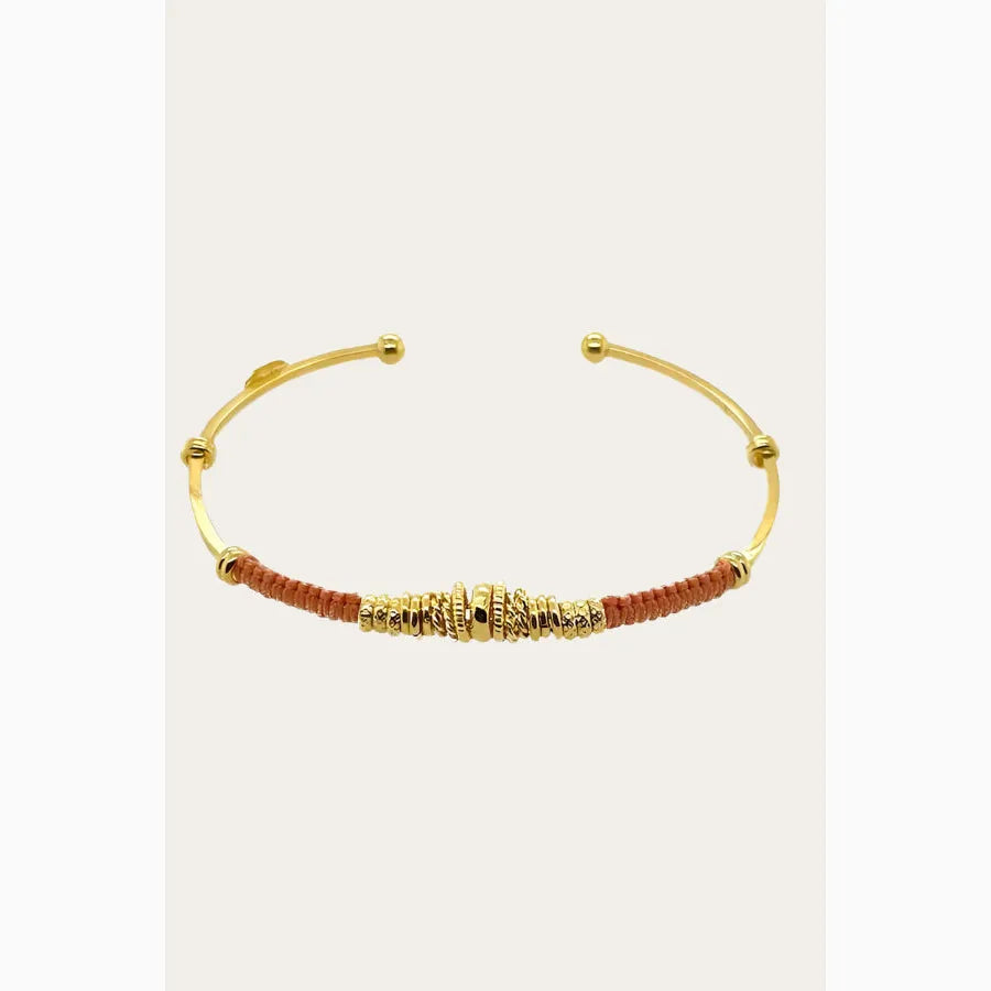 gold bangle with coloured thread and gold rings, on flat lay neutral surface available at The Artemis Edit
