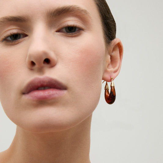 Close-up of a woman wearing a gold earring with a clear background