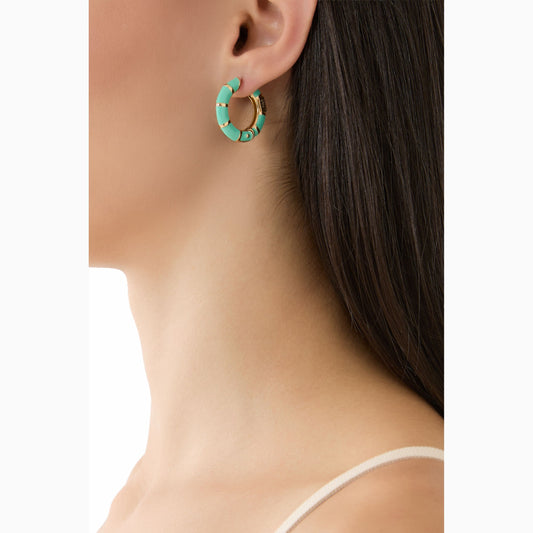 Close-up of a turquoise hoop earring worn by a person on a white background