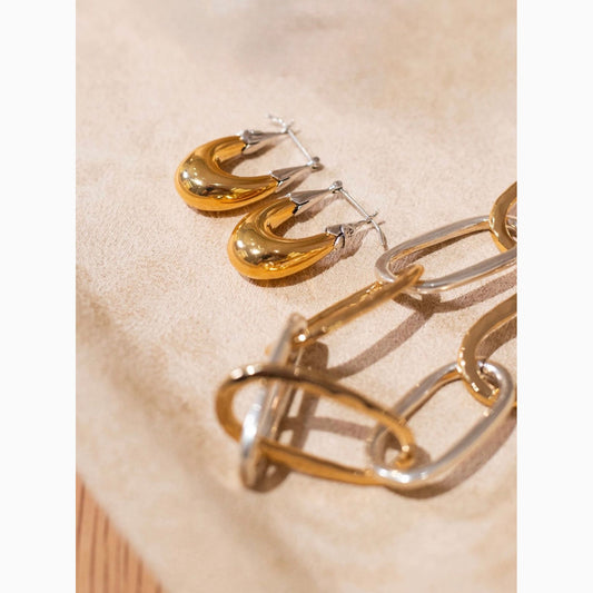 Gold and silver hoop earrings on a beige fabric background