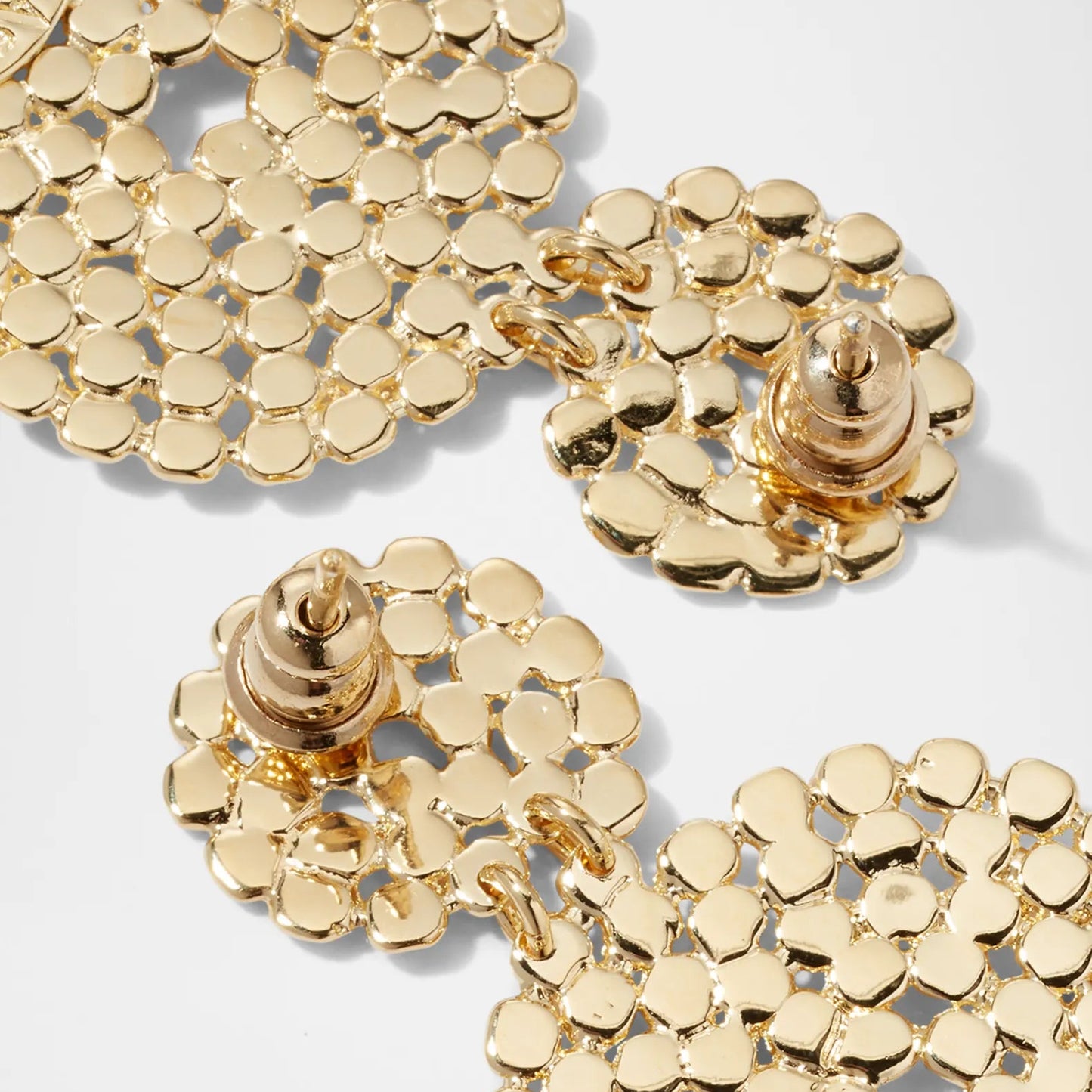 Gold earrings with a textured design on a light gray background