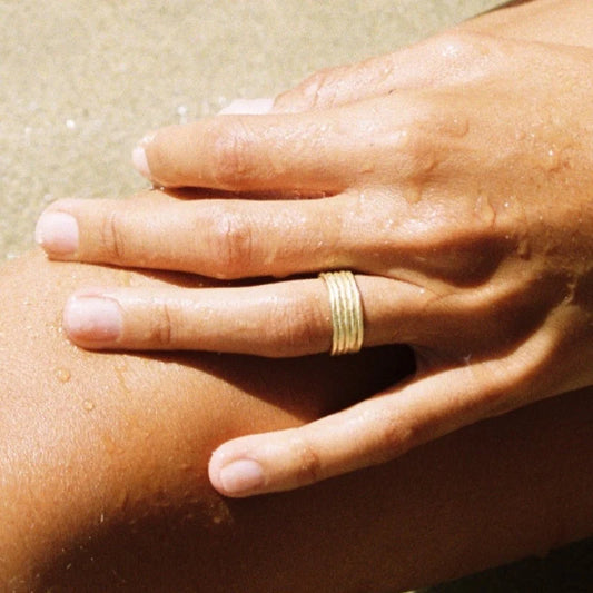 Hand with a gold ring on a sunlit surface