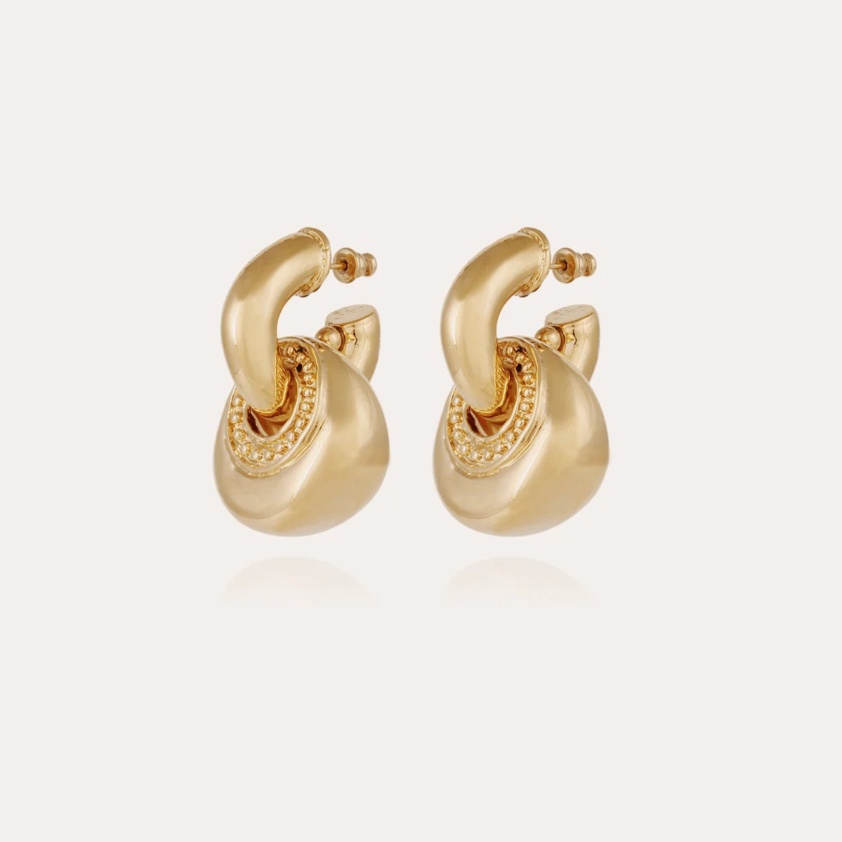 Pair of gold hoop earrings on a light beige background