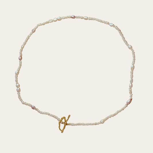 Pearl necklace with a gold clasp on a brown background