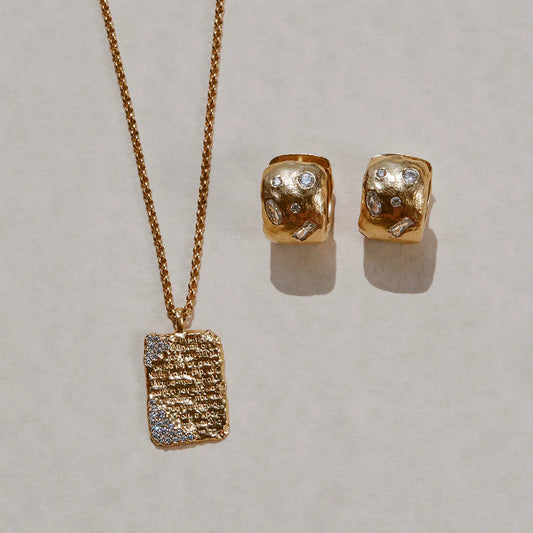 Gold necklace and earrings on a light gray background