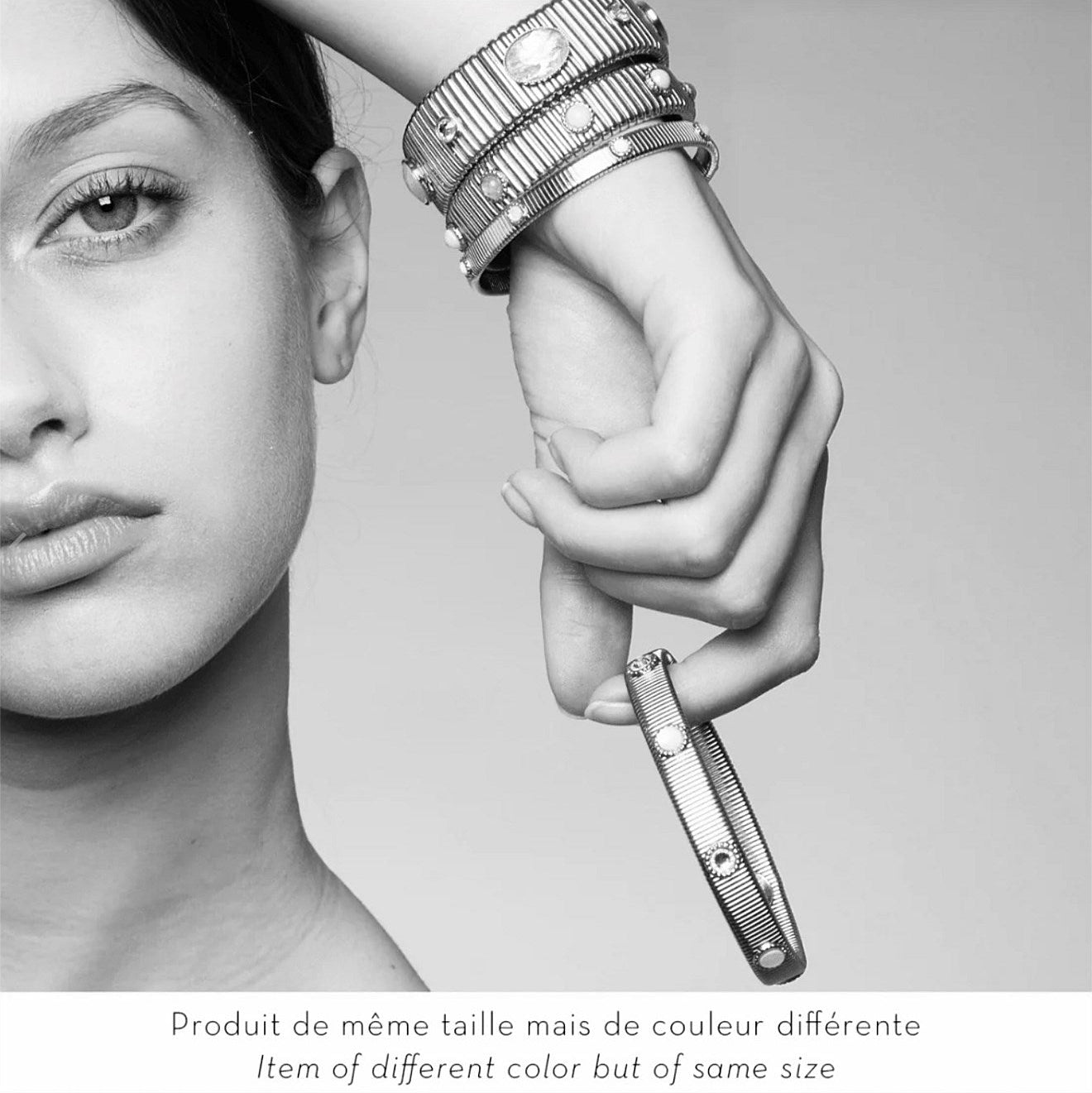 woman wearing stacked bracelets and holding one with stones in black and white