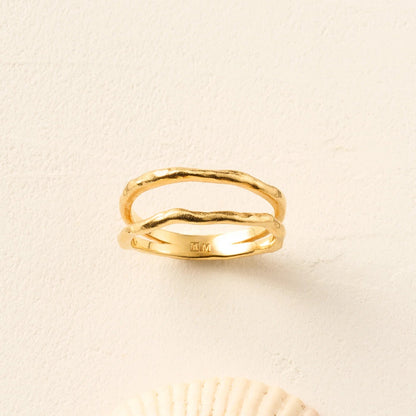Gold ring on a beige background with a shell at the bottom