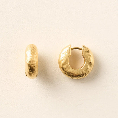 Pair of gold hoop earrings on a beige background